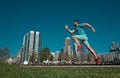 Full length of healthy man running and sprinting outdoors near city skyline. Male urban runner. Dynamic jump movement.