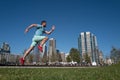 Full length of healthy man running and sprinting outdoors near city skyline. Male urban runner. Dynamic jump movement.