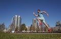 Full length of healthy man running and sprinting outdoors near city skyline. Male urban runner. Dynamic jump movement.