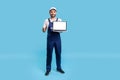 Full length high-qualified worker man in uniform showing thumbs up and holding laptop with mock up