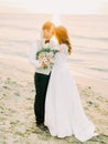 The full-length of the hugging newlyweds at the background of the sunset in the sea. Royalty Free Stock Photo