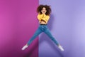 Full length image of amazed happy curly woman swearing casual clothes smiling and jumping