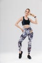 Full length image of athletic blond woman 20s dressed in sportswear doing workout in gym with jumping rope