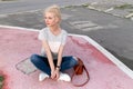 Full length image of a beautiful young woman with blond hair, posing and looking at the side, sits down. Royalty Free Stock Photo