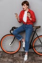 Full length image of confused woman holding smartphone by bicycle Royalty Free Stock Photo