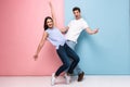 Full length image of excited man and woman in casual wear laughing and having fun together, isolated over colorful background Royalty Free Stock Photo