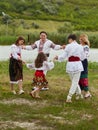 Full length image of a family with kids in traditional romanian dress in a countryside, park. Dancing outside. Royalty Free Stock Photo