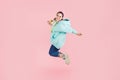 Full length image of happy brunette woman with canecalons in oversize hoodie jumping and looking at the camera over pink Royalty Free Stock Photo