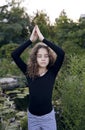 Full length image of a little girl with curly hair in doing yoga in the park. Healthy lifestyle Royalty Free Stock Photo