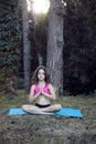 Full length image of a little girl with curly hair in sports wear doing yoga in the park, in paceful place Royalty Free Stock Photo