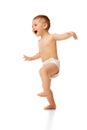 Full-length image of little happy baby boy, child standing in diaper, playing, jumping isolated over white studio Royalty Free Stock Photo