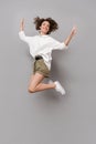 Full length image of positive girl 20s smiling and jumping, isolated over gray background Royalty Free Stock Photo