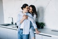 Attractive young woman and handsome man are enjoying spending time together while standing on light modern kitchen with cup of Royalty Free Stock Photo
