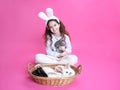 Full length image of a smiling little girl with white bunny ears, looking at camera, isolated on a pink background. Royalty Free Stock Photo