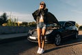 Full-length image of woman standing in front of black car with open hood Royalty Free Stock Photo
