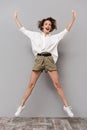 Full length image of young european woman 20s smiling and jumping, isolated over gray background Royalty Free Stock Photo