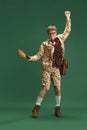 Full-length image of young guy in retro clothes in image of boy scout dancing, having fun against green studio Royalty Free Stock Photo