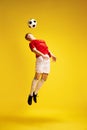 Full-length image of young man in uniform, soccer player, enthusiast in motion, training, hitting ball with head against Royalty Free Stock Photo