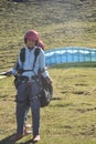 Full length of a Indian young male tourist preparing for paragliding flight with professional paraglider