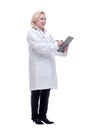 Profile of a pretty doctor with white lab coat, stethoscope smiling and writing notes in clipboard Royalty Free Stock Photo