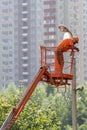 Full length, legs, body, size vertical portrait of people, person workman in orange uniform, helmet stand and raised up in bucket