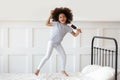 Girl jumping on bed holding hairbrush like microphone and singing Royalty Free Stock Photo