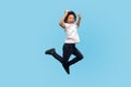 Full length, lively energetic little boy in T-shirt and denim jumping in air screaming with happiness