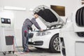 Full length of male engineer examining car in automobile repair shop