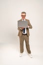 In a full-length the mature businessman holds a laptop