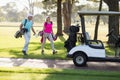 Full length of mature golfer couple by golf buggy