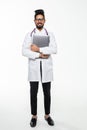 Full length of a medical indian doctor standing in the studio while working with laptop, isolated on white background Royalty Free Stock Photo