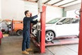 Car Mechanic Operating Hydraulic Lift In Repair Shop Royalty Free Stock Photo