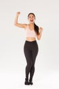 Full length of motivated and excited female athelte, asian fitness girl in activewear fist pump and shouting encouraged Royalty Free Stock Photo