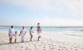 Full length of a multi generation family on vacation walking along the beach together. Mixed race family with two Royalty Free Stock Photo