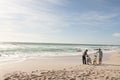 Full length of multiracial senior couple walking with bicycles on shore at beach during sunny day Royalty Free Stock Photo