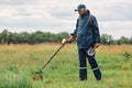 Full length outdoor portrait of numismatist in jacket and cap, holding in hands shovel and metal detector, looking for gold or Royalty Free Stock Photo