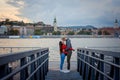 Full-length outdoor shot of the loving couple rubbing noses on the iron pier near River Danube in Budapest, Hungary. Royalty Free Stock Photo