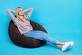 Full length photo of adorable cute girl dressed grey sweatshirt sitting bean bag arms behind head empty space isolated Royalty Free Stock Photo