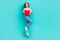 Full length photo of adorable cute lady wear striped t-shirt holding heart jumping empty space isolated turquoise color