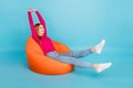 Full length photo of adorable sweet woman wear pink shirt sitting beanbag stretching smiling isolated blue color Royalty Free Stock Photo