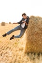 Full length photo of amusing man 30s walking through golden field, and having fun near big haystack during sunny day
