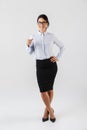 Full length photo of attractive businesswoman wearing eyeglasses standing in the office, isolated over white background Royalty Free Stock Photo