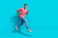 Full length photo of attractive funky guy dressed pink polo running fast jumping empty space isolated blue color