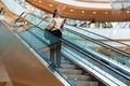 Full length photo of beautiful pretty woman smiling and holding clipboard while going down escalator in building indoors Royalty Free Stock Photo