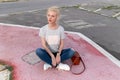 Full length photo of a beautiful young woman with blond hair, posing and looking at the side, sits down. Royalty Free Stock Photo