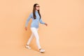 Full length photo of boss young lady go wear eyewear pullover trousers sneakers isolated on beige background