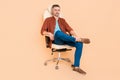 Full length photo of bossy smart partner middle-aged guy sit leather chair isolated over pastel beige color background