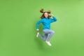 Full length photo of brunette ponytail haired little girl jump up run empty space blue hoodie weekend isolated on green