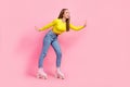 Full length photo of charming excited school girl dressed yellow crop top riding rollers empty space isolated pink color