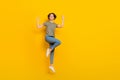 Full length photo of charming lucky lady wear striped t-shirt jumping high rising fists empty space isolated yellow